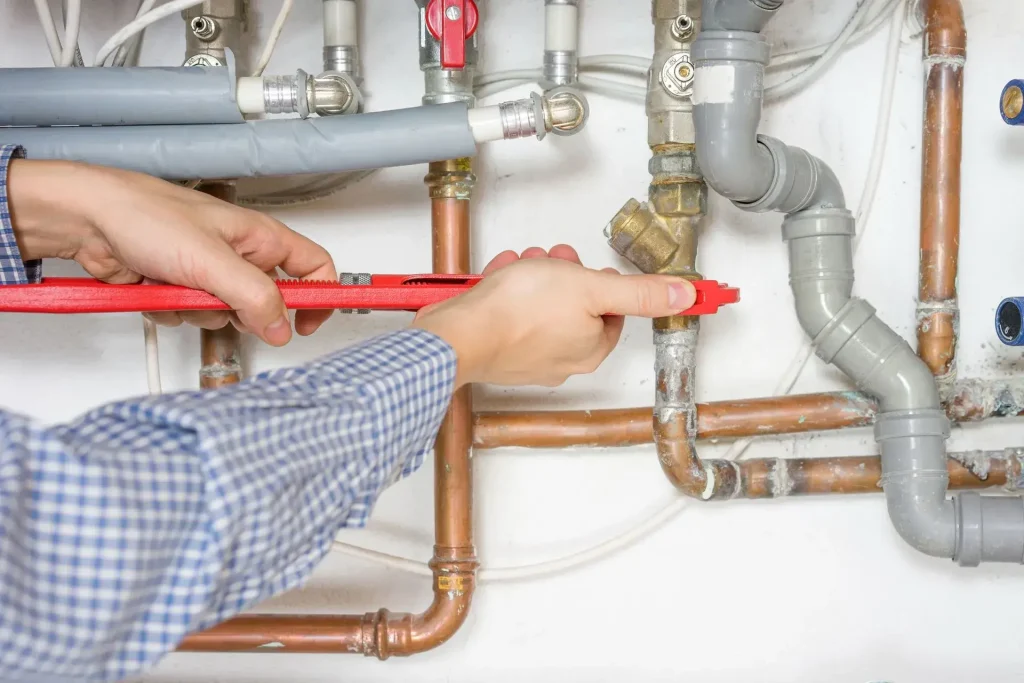 Person adjusting plumbing pipes with wrench
