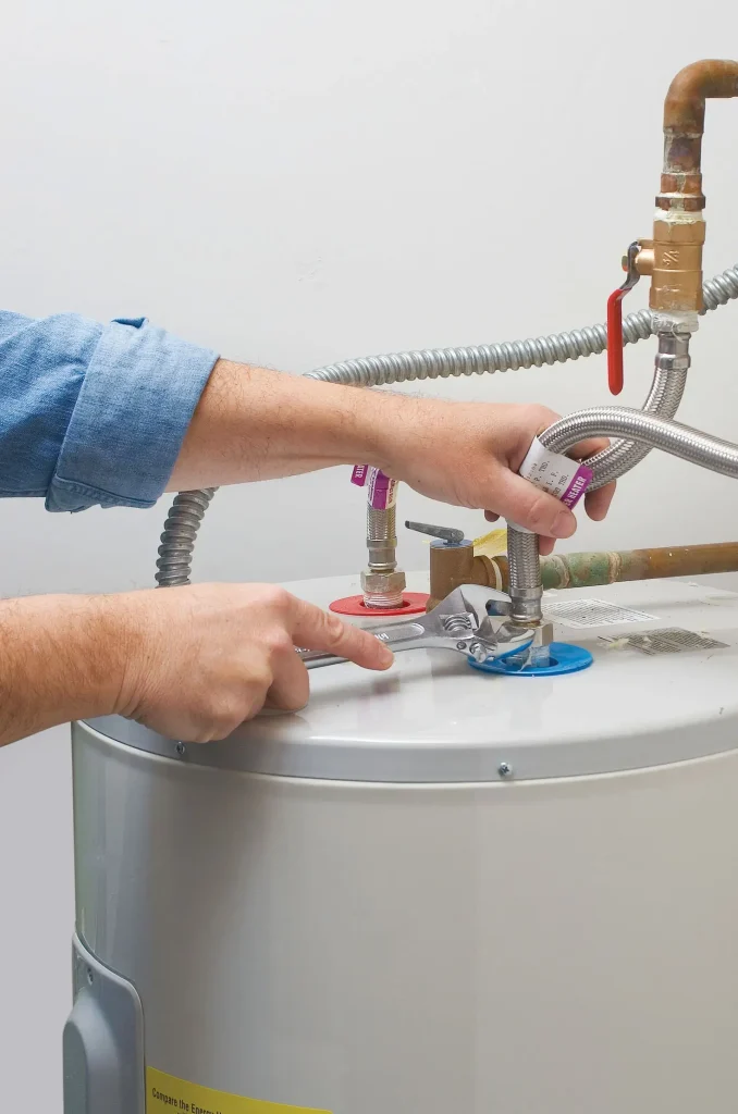 Person repairing a water heater connection.